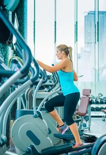 Mulher usando aparelho elíptico na academia