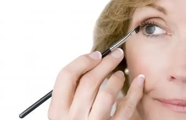 Femme mûre appliquant le maquillage d'oeil