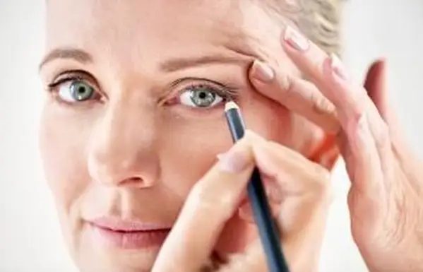 Femme mûre appliquant l'eye-liner