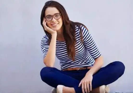 אישה מחויכת בסגנון קלאסי יושבת על הרצפה