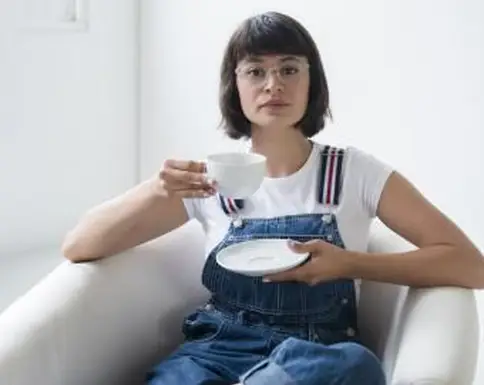 אישה היפסטרית בסרבל שותה תה