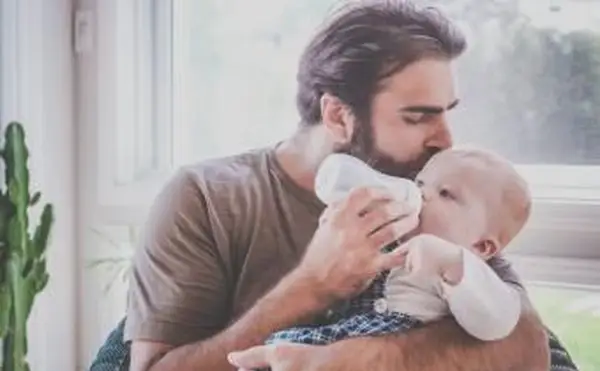 Pai alimentando seu filho com uma garrafa de leite