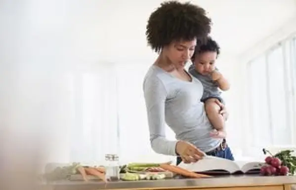 Matka czyta książkę kucharską, trzymając synka