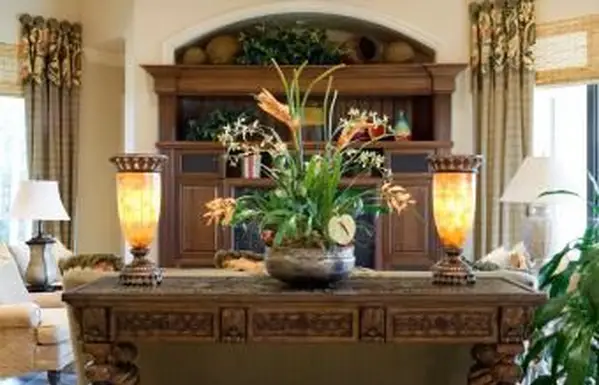 Schöner geschnitzter Konsolentisch mit Seidenpflanze und beleuchteten Leuchten in einer Höhle