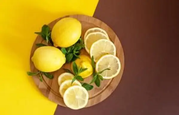 Tabuleiro com limões cortados e raspas na mesa de madeira