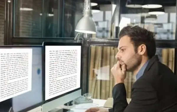 Spisovateľ pozerajúci rukopis na monitoroch