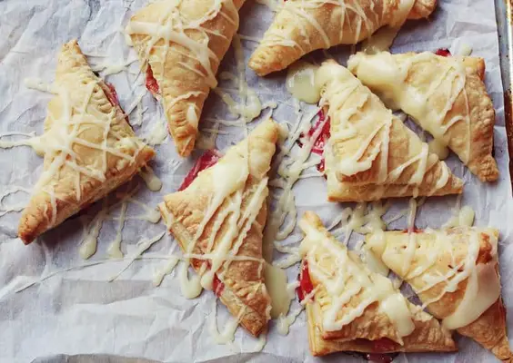 Baked and glazed rhubarb toaster strudel cooling on a pan. 