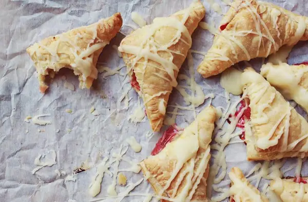 parchment paper with strudel on it with a bite taken out of one. 