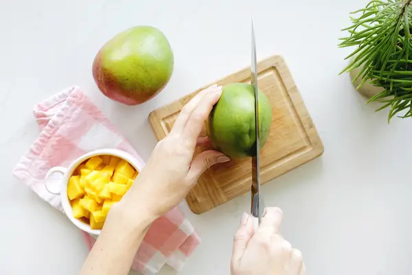 Cutting into mango on cutting board