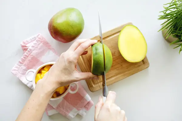Cutting into mango on cutting board