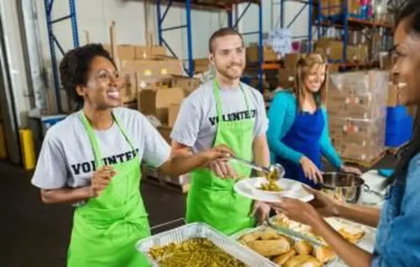Voluntarios que sirven comida caliente en un comedor de beneficencia