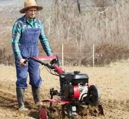 男は耕運機で土地を耕作します