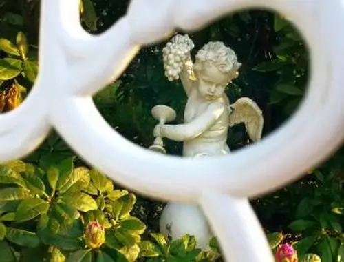 Estátua de anjo em meio a plantas no jardim