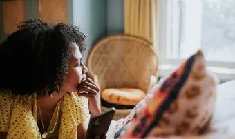 Žena vypadá roztržitě a zamyšleně, když leží na posteli