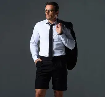 muž v šortkách drží bundu na rameni