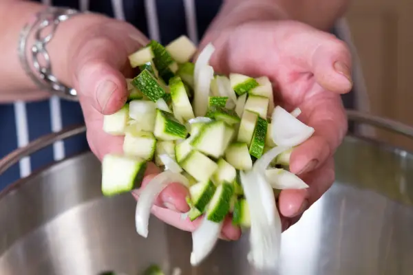 Adding the courgettes and onions to the saucepan