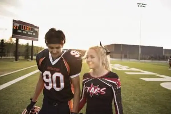 Nastoletnia cheerleaderka z liceum i piłkarz trzymający się za ręce