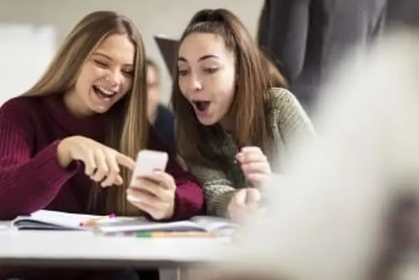 Las adolescentes en clase mirando teléfono celular