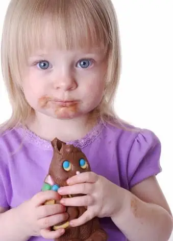 Maluch dziewczynka je czekoladowego Zajączka wielkanocnego