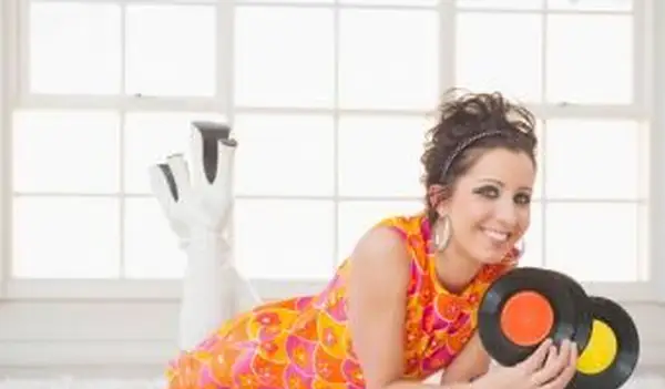 kobieta w nostalgicznej sukience trzymająca płyty winylowe