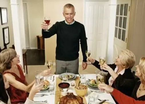 Hombre liderando un brindis en una comida de Acción de Gracias