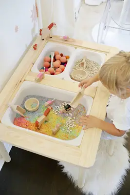 a blonde girl playing at the wooden sensory table