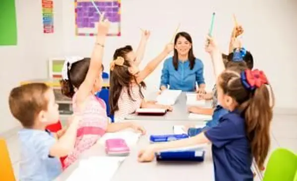 Bambini che alzano la mano a scuola