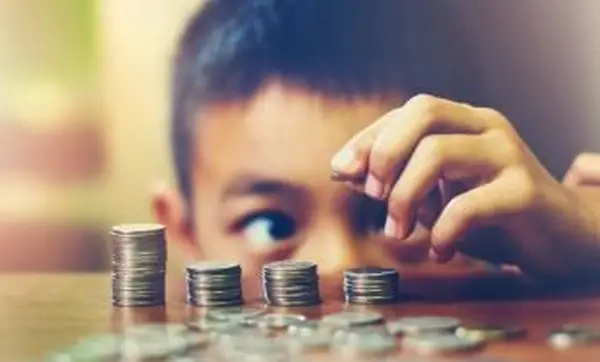 Chico apilando monedas en la mesa