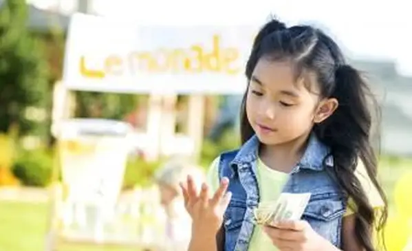 Niña cuenta dinero hecho de puesto de limonada