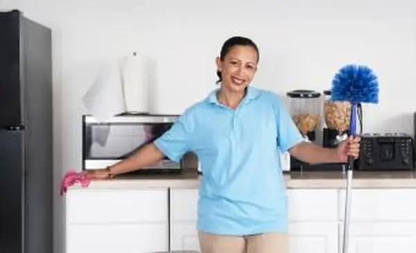 Mujer limpiando una habitación con un plumero de telarañas
