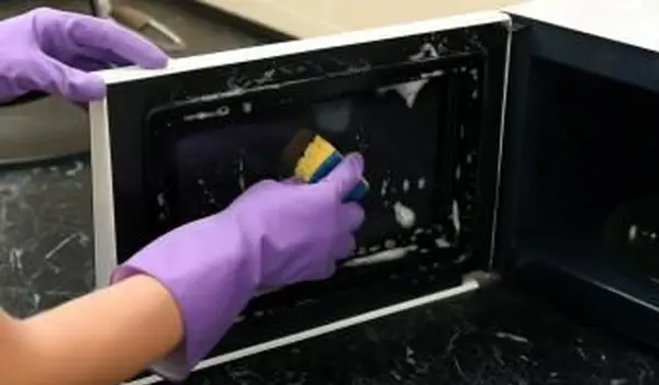 mujer limpiando horno microondas