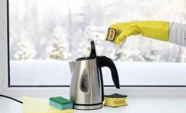 Wlewanie destylowanego białego octu do dzbanka do kawy