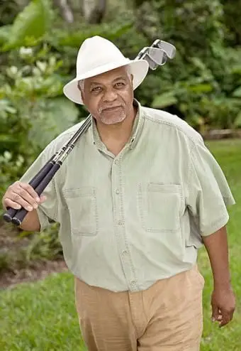 modelo masculino maduro segurando tacos de golfe