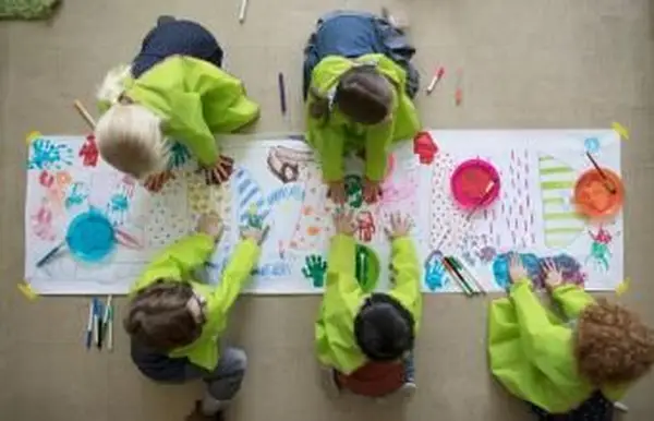estudiantes de preescolar usando pinturas de dedos en póster