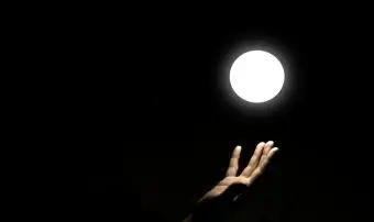 Ręka dotykająca świecącego źródła białego światła