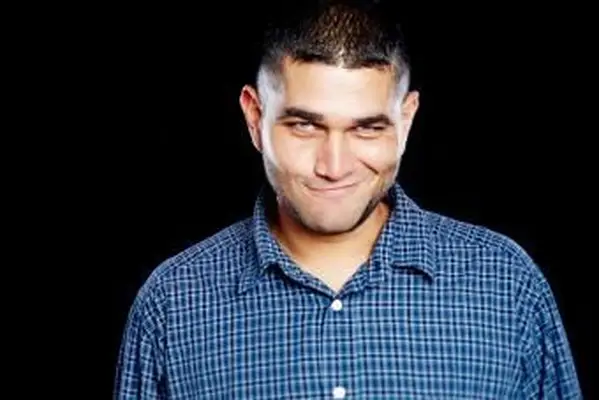 Homem sorrindo ironicamente para a câmera