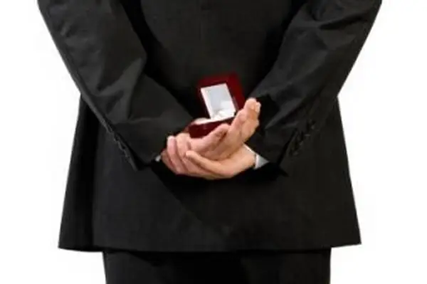 איש מחזיק טבעת אירוסין מאחורי גבו