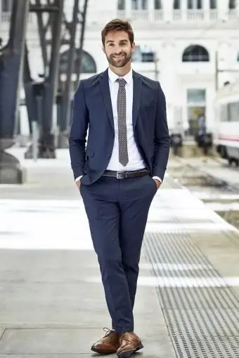 Dirigente sorridente con le mani in tasca alla stazione