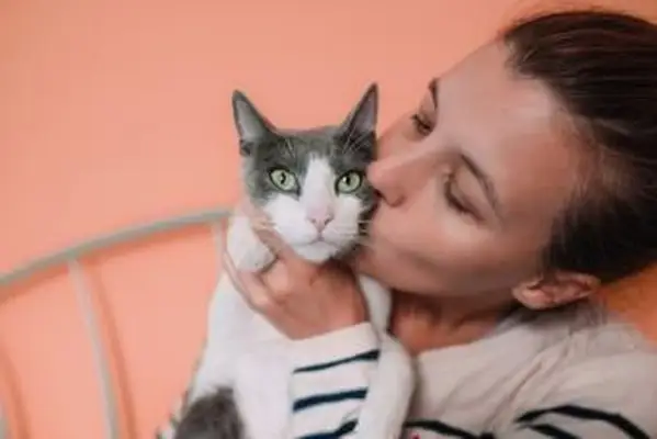Mujer besando gato gris y blanco