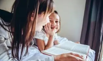 אמא ובת קוראת ספר במיטה