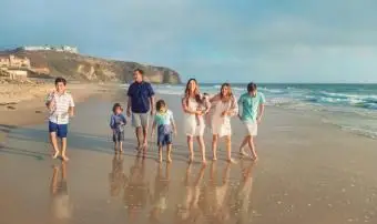 Grande família mesclada caminhando na praia