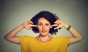 Mulher tapando os ouvidos com os dedos