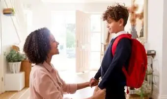 Madre single a casa che prepara il figlio con l'uniforme per il primo giorno di scuola