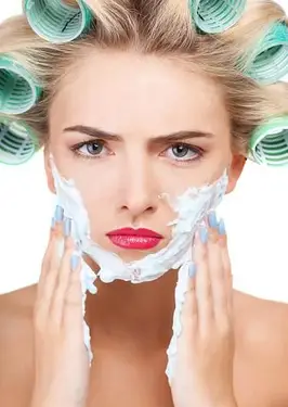 顔を泡立てるカーラーでしかめっ面の女性