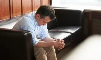 Padre ansioso seduto su un divano e con la testa appesa