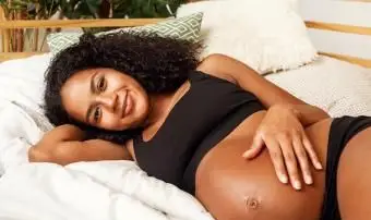 Souriante jeune femme enceinte allongée sur le lit