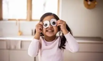 Ragazza che gioca con gli occhietti stupidi a casa