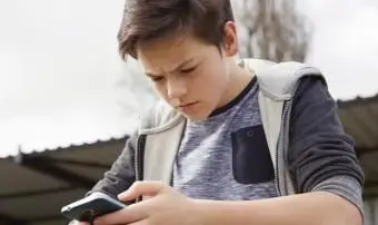 Adolescente confuso che guarda lo smartphone