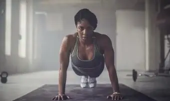 Mujer haciendo flexiones en el gimnasio oscuro