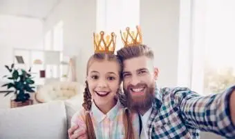 自分撮りをしながら王冠を身に着けているかわいい子供とスタイリッシュなパパ
